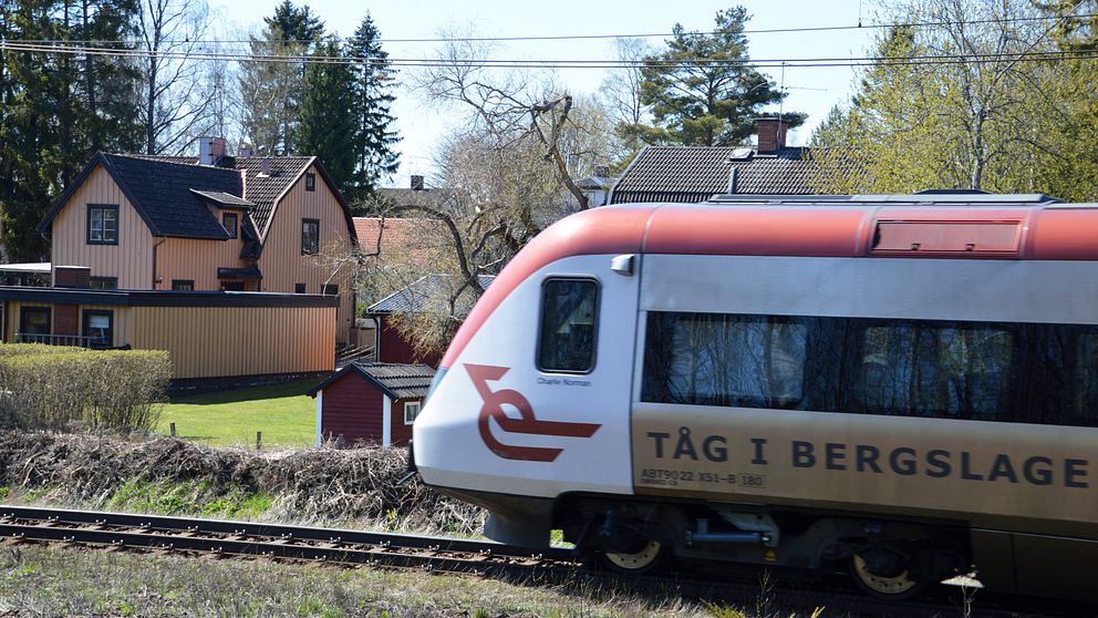 Passageratåg passerar framför villor.