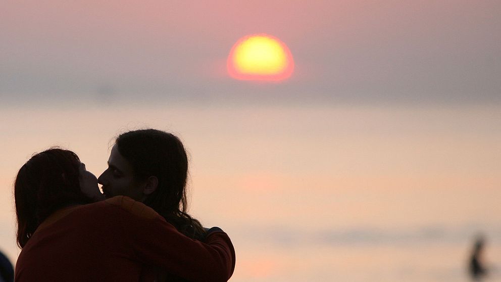 Ett par som kysser varandra i solnedgången.