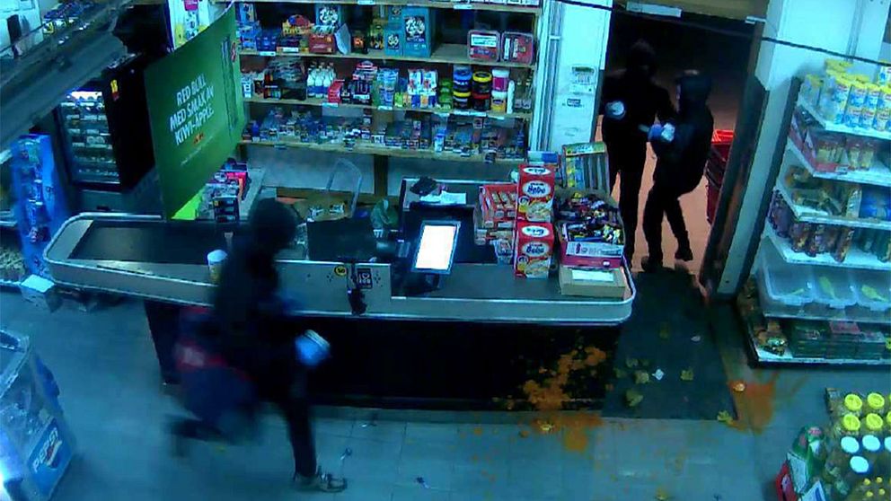 I butikens övervakningskamera fångas rånarna som flyr. Golvet har fläckats av innehållet i de krossade glasburkarna.