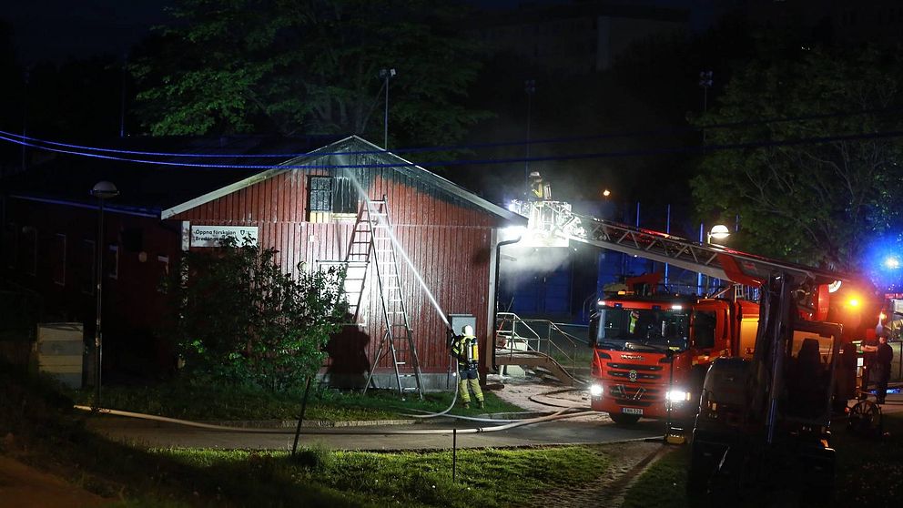 Brandbilar vid förskolan som är brandhärjad längs taket.