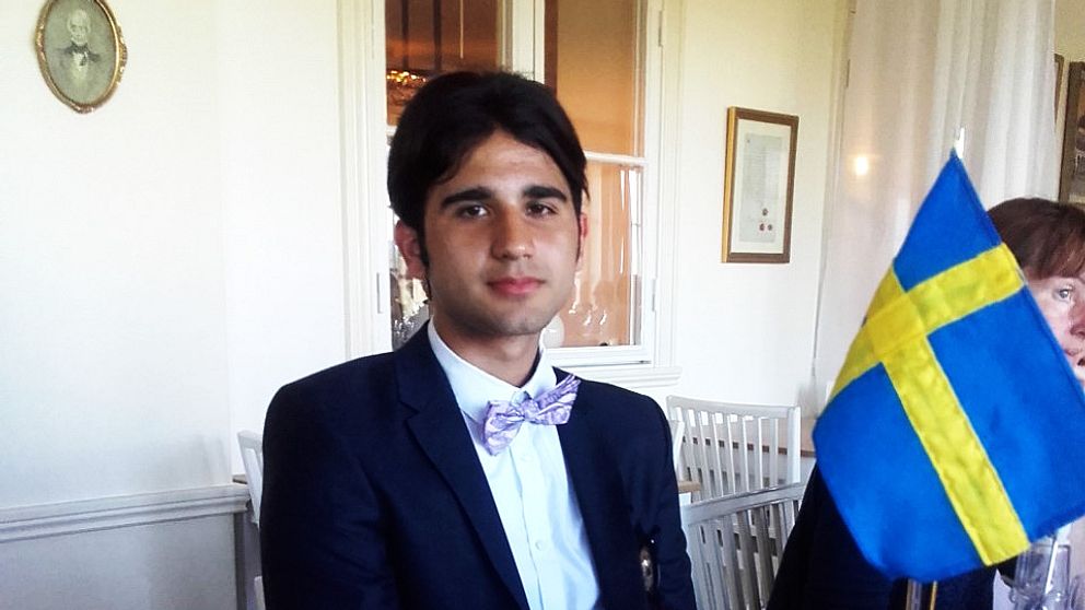 Jakob Ashour som fått svenskt medborgarskap sitter bredvid en svensk flagga.