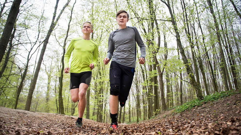 Två unga killar springer mot kameran i skogen