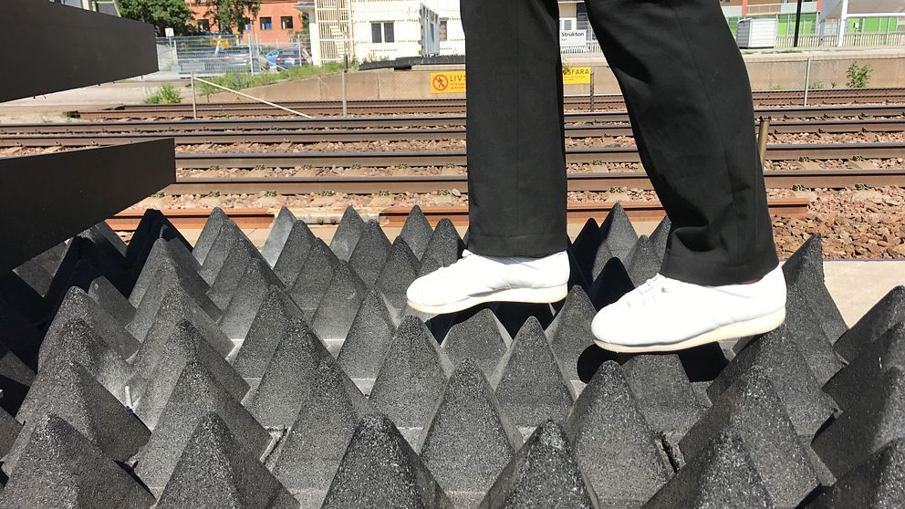 fötter går på pyramidformade gummimattor vid järnvägsspår