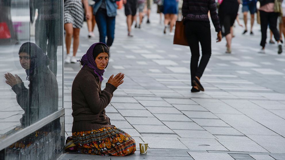 En kvinna tigger vid Sergels torg i Stockholm.