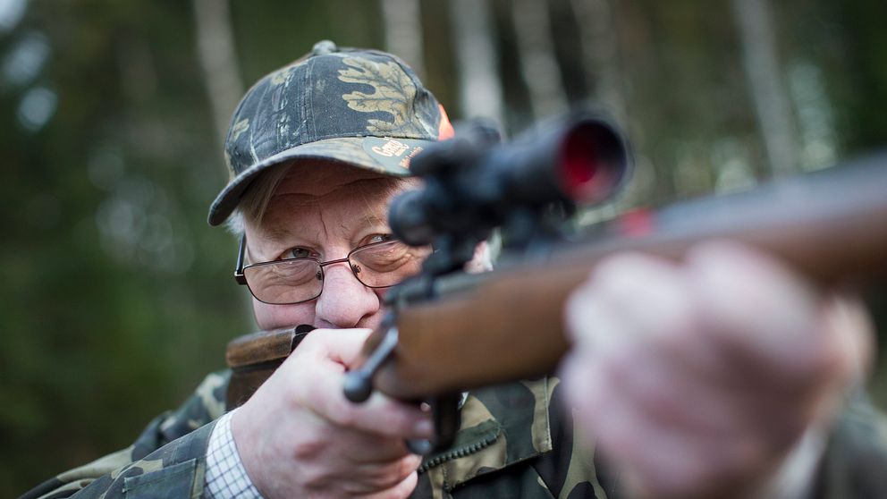 en man i kamouflagekläder siktar med gevär