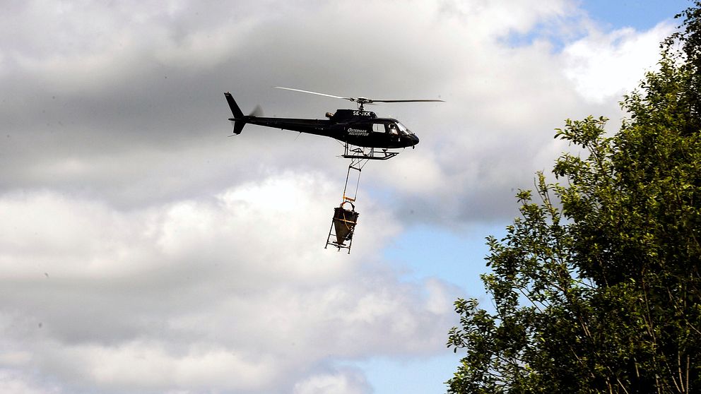 en helikopter flyger med behållare hängande under