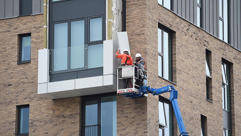 Arbetare plockar bort fasadmaterial från en byggnad i Wythenshawe i Manchester.