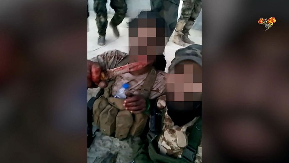 Två irakier visar stolt upp en blodig kniv för kameran.