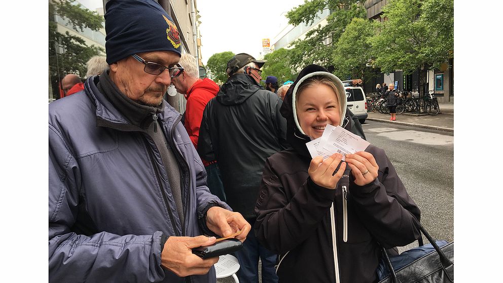 medelålders man och ung kvinna med biljetter, ute på på gatan