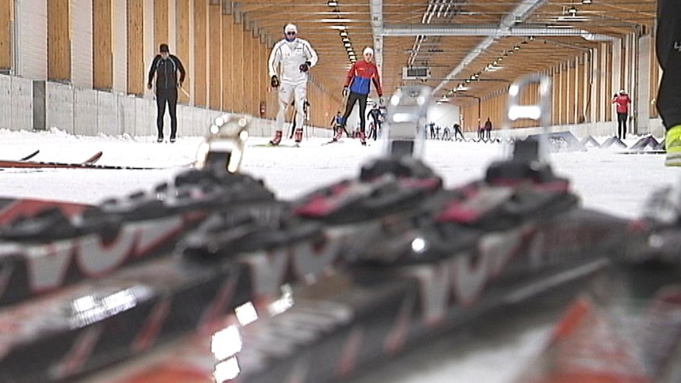 Skidor på backen i förgrunden och människor som åker skidor i bakgrunden.