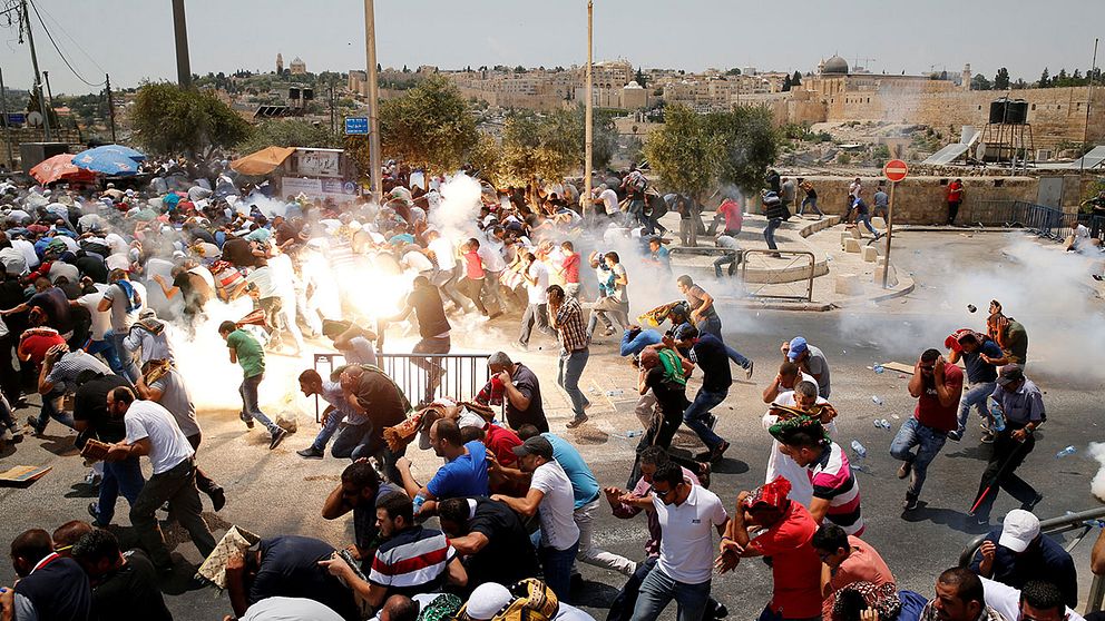 Palestinier utanför muren i Jerusalem flyr undan tårgas från israeliska säkerhetsstyrkor under fredagen.