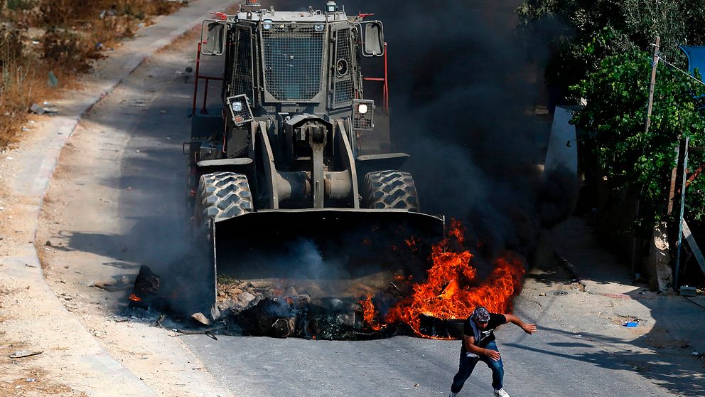 En palestinsk ungdom springer ifrån bulldozer i byn Kobar, i närheten av Ramallah på Västbanken.