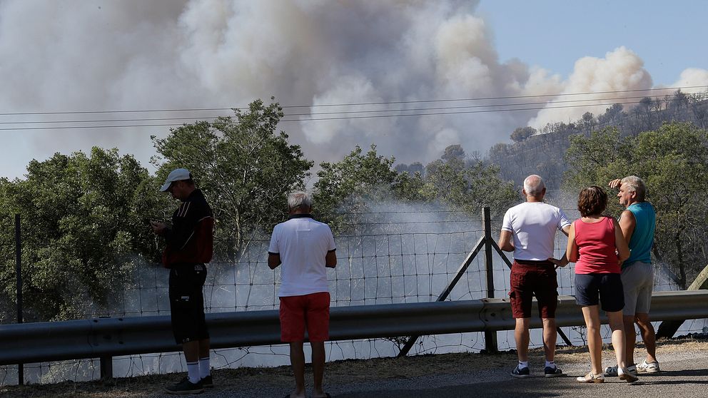 Invånare ser på medan brandrök stiger ur skogen kring La Londe-les-Maures, där den kraftigaste branden i området ska ha haft sitt ursprung.