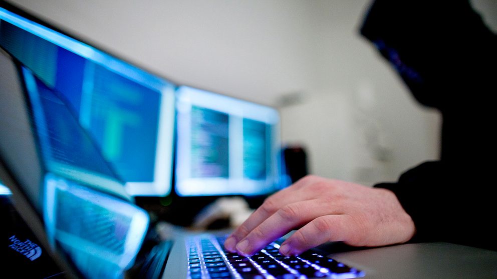 En hackare framför en dator.