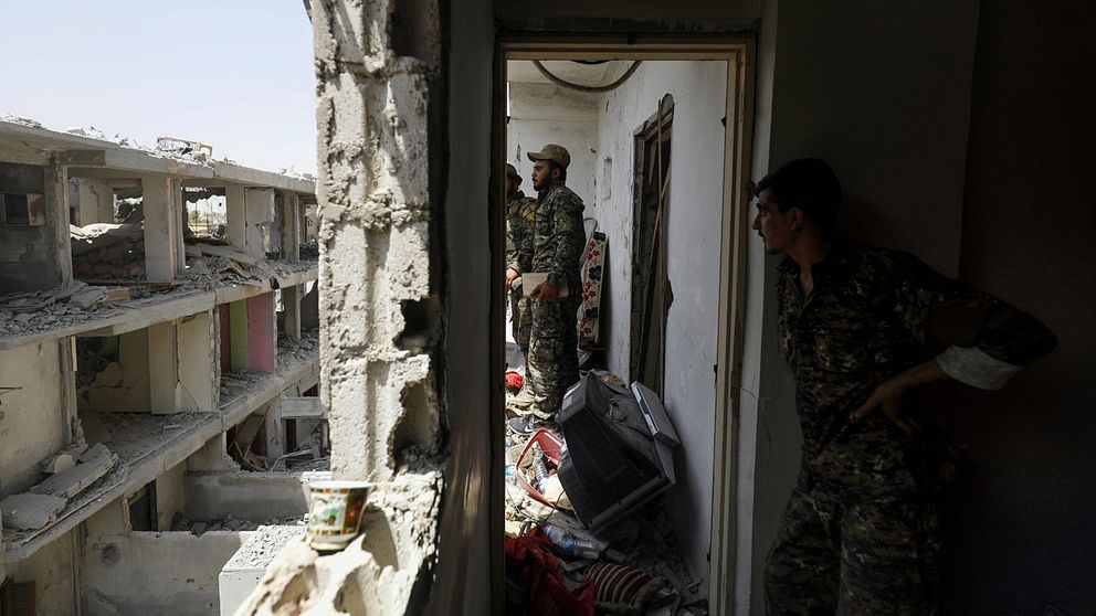 Stridande medlemmar av YPG och SDF genomsöker förstörda byggnader i Raqqa, Syrien.