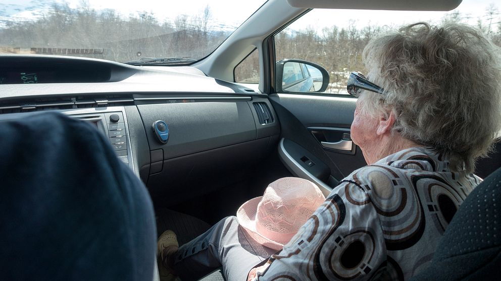 Äldre kvinna sitter i passagerarsätet i en bil.