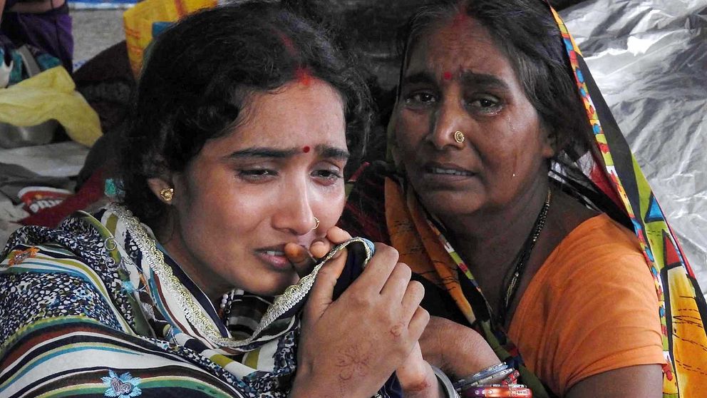Två indiska kvinnor som gråter tröstar varandra.