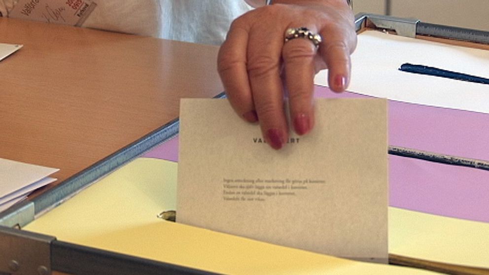 En hand som lägger en valsedel i en röstlåda, kyrkovalet