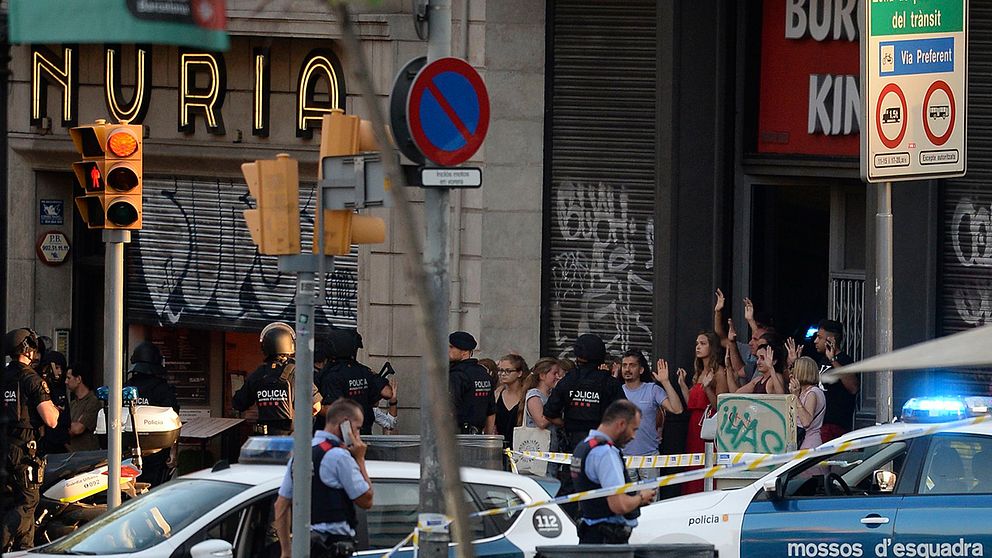 Människor lämnar en snabbmatsrestaurang efter attacken och ombeds hålla händerna i luften av polisen.