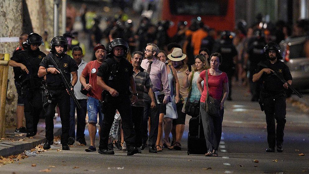 En grupp människor eskorteras av poliser i Barcelona efter misstänkta terrordådet.