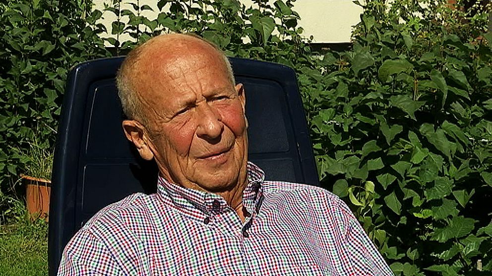 Arne Carlsson, en man, sitter i rutig skjorta ute i solen och tittar snett bredvid kameran.