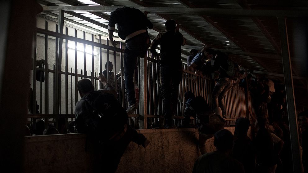 Palestinier som klättrar över ett galler.
