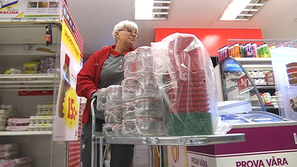 medelålders kvinna puttar vagn med varor i matbutik