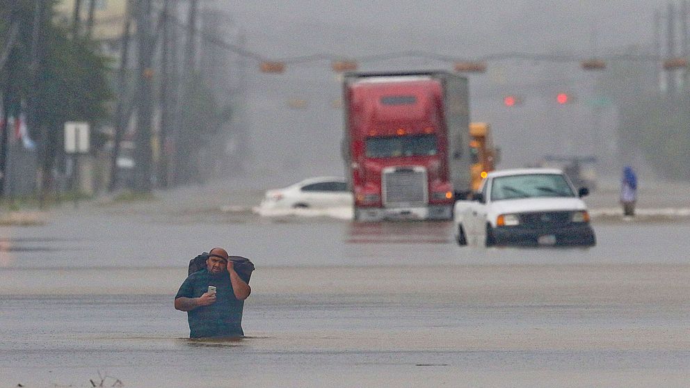 En man bär med sig sina tillhörigheter medan han tar sig fram på en översvämmad gata i Houston, Texas den 27 augusti.