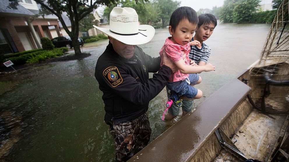 Sheriff Troy Nehls och  Lucas Wu hjälps åt att lyfta upp Ethan Wu i en båt. Bilden är tagen i Fort Bend County, Texas.