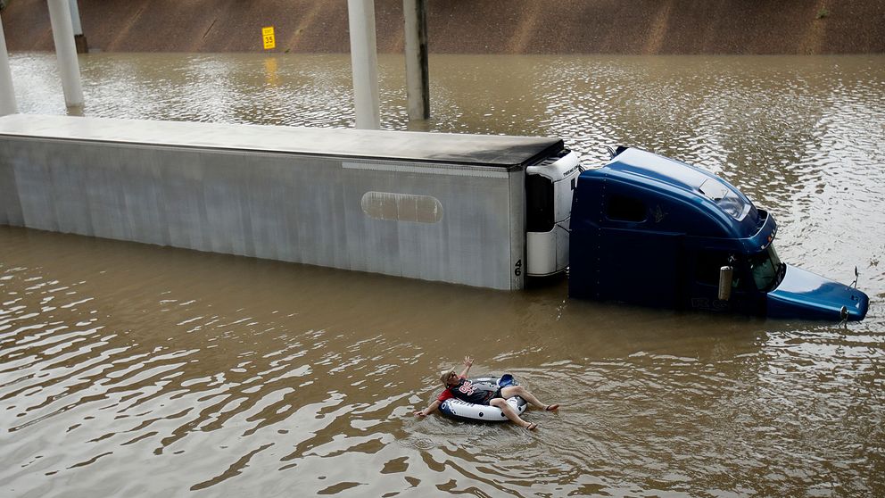 En man flyter nedför en översvämmad motorväg i centrala Houston i en badring.