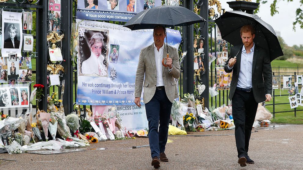 Prins William, till vänster, och prins Harry vid Kensington Palace där människor lagt blommor, bilder och minnestexter inför 20-årsdagen av deras mors, prinsessan Dianas död i en trafikolycka i Paris.
