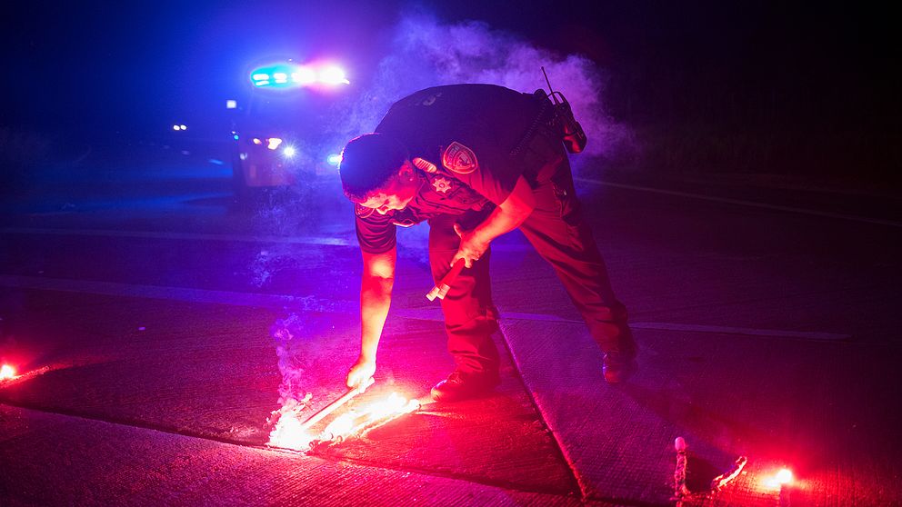 En polis lägger ner säkerhetsbloss för att blockera vägen till Arkema kemikalieanläggning utanför Houston