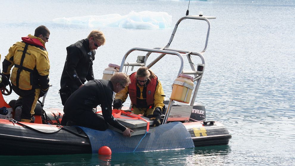 Bild på forskarna i båt när de lägger i värmepaneler i vattnet