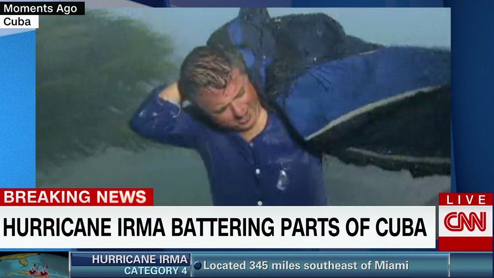 Tv-bild av Patrick Oppmann försöker ta på sig en jacka i det kraftiga regnet.