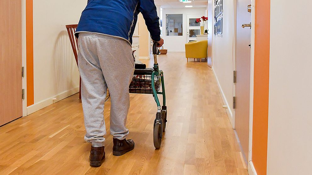 anonym äldre person går med rollator i korridor