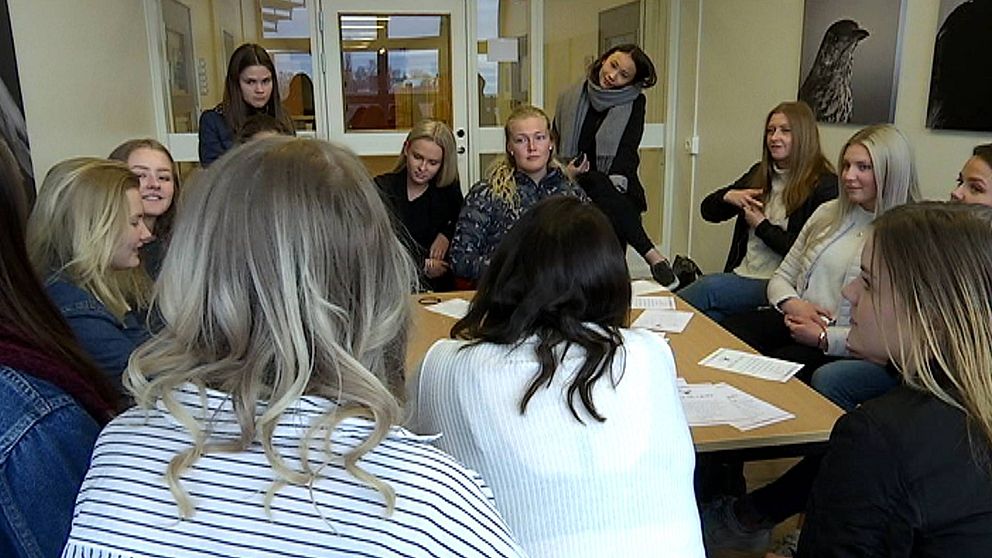 Gymnasieelever, alla tjejer, sitter runt ett bord och pratar med varandra.