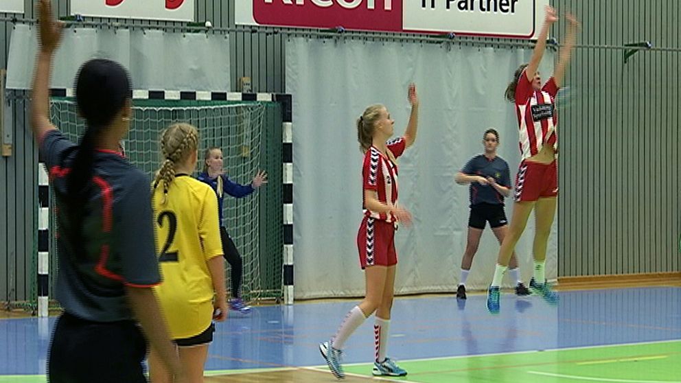 Handbollslag tävlar i Örebrpcupen. En spelare hoppar upp och försöker ta bollen.