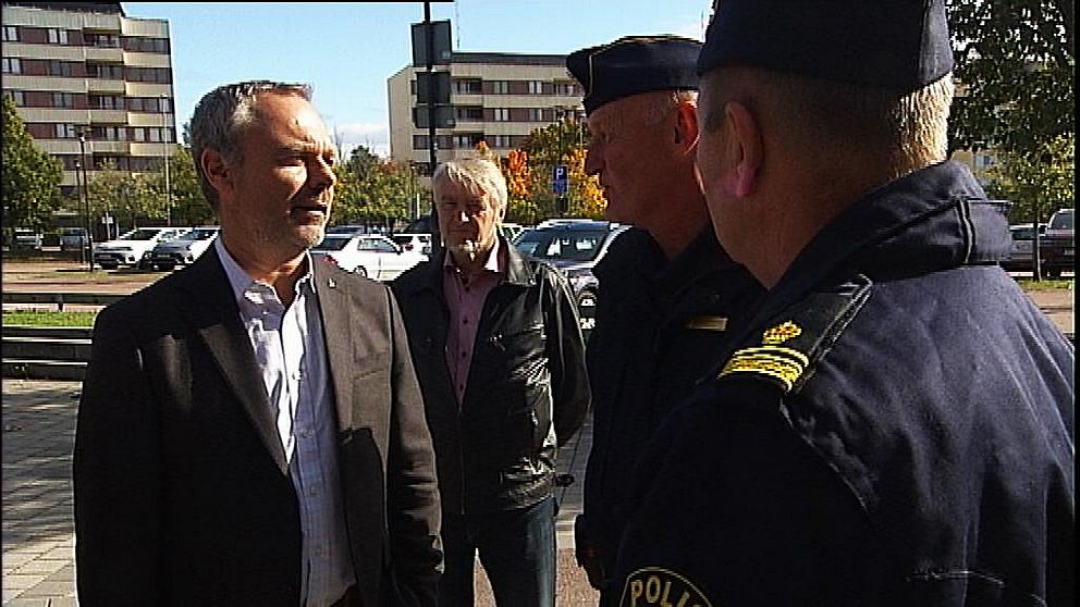 Jan Björklund står till vänster i bilden och mittemot honom står två poliser. I bakgrunden står även ytterligare en man