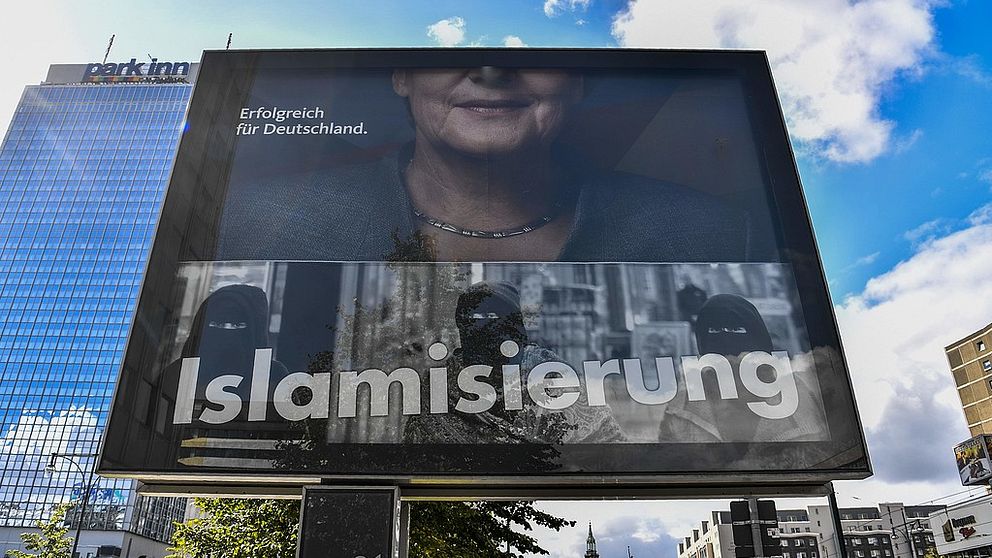 En valaffisch som visar en halv Angela Merkel och ordet islamisering.