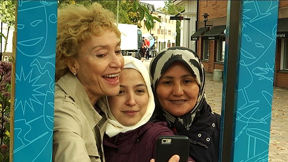 De tre kvinnorna syns leende inuti en blå ram. De håller en mobil framför sig, ser ut som att de tar bilder.