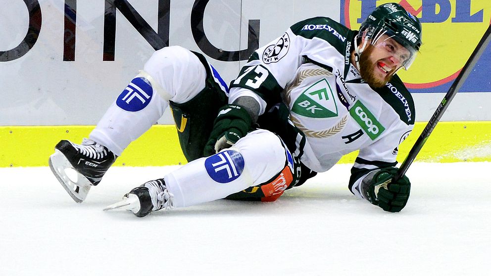 Anton Grundel ligger på isen med handen mot knäet. Han grimaserar med tandskyddet mellan tänderna
