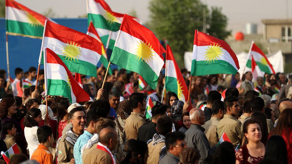 En folksamling håller upp kurdiska flaggor.
