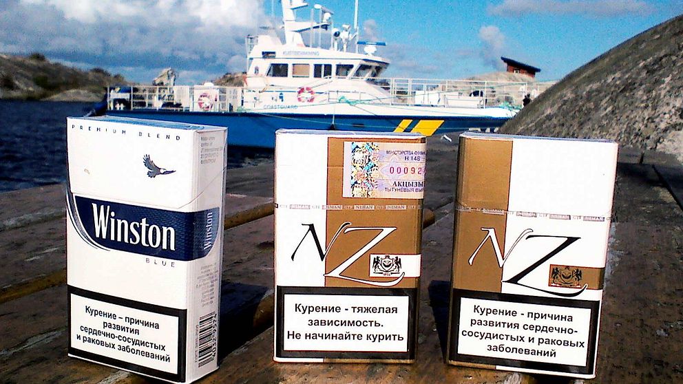Cigarettförpackningar framför Kustbevakningens båt.