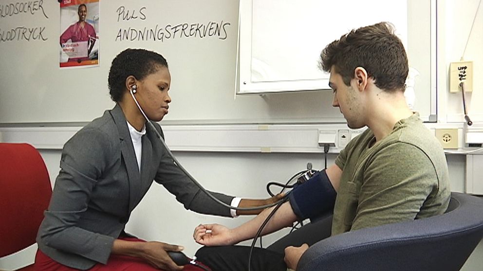 en tjej sätter blodtrycksmätare på armen på en kille kille