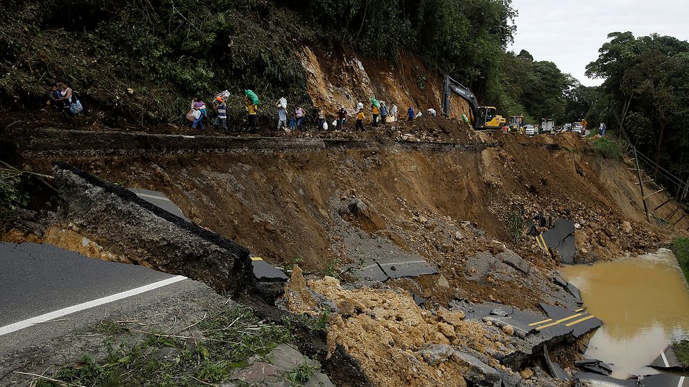 Människorna som går längs vägraset i Casa Mata, Costa Rica, färdades med buss som inte kunde ta sig längre när vägen rasade, orsakat av stormen Nate.