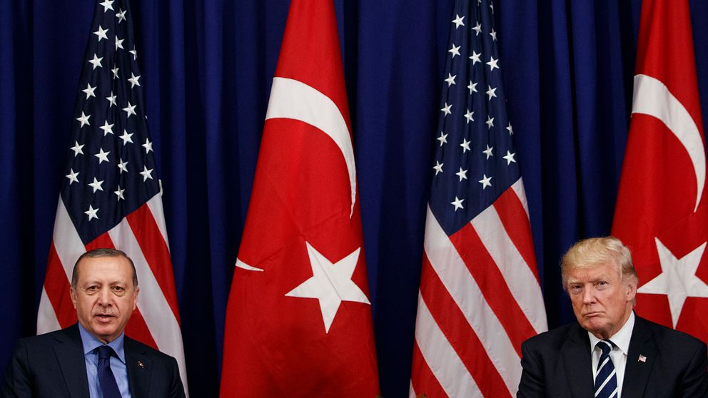 Till vänster president Erdogan och till höger president Trump. De sitter med ett stort avstånd mellan varandra. I bakgrunden ses två amerikanska och två turkiska flaggor.