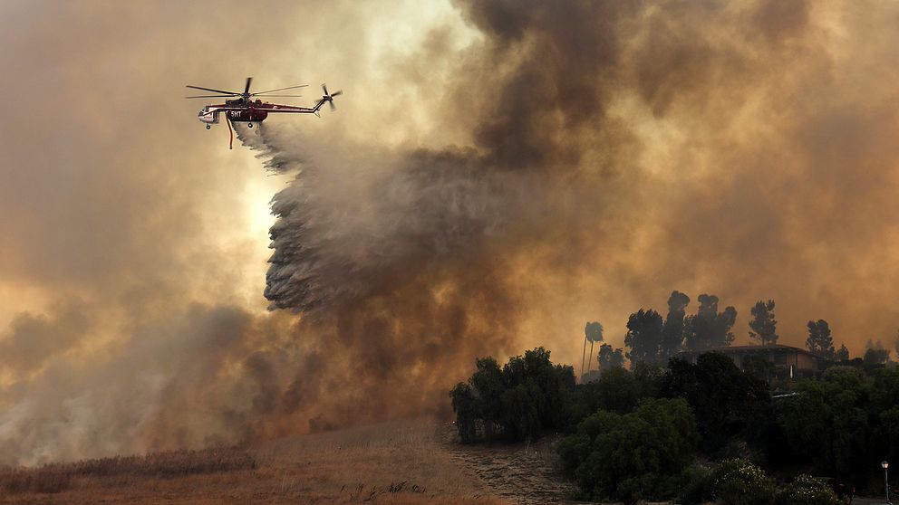 En brandhelikopter försöker rädda ett hus från branden genom att spruta vatten, Orange, Kalifornien.