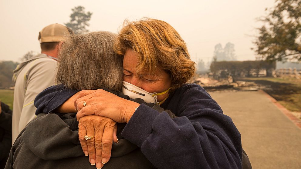 Kim Graves kramar grannen Susan Gaynard. Bådas hem har brunnit ner i Sonoma County i Kalifornien, USA