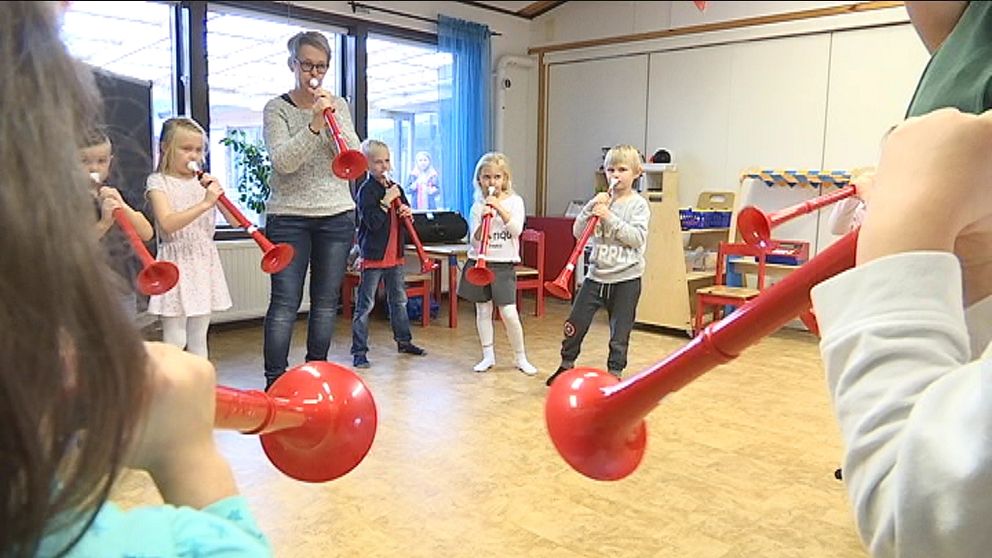 Barn och förskolepedagog spelar blåsinstrumentet pbuzz.