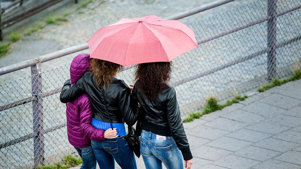 Kvinnor som går med paraply.